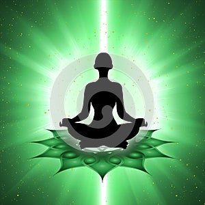 Silhouette of meditating person with heart chakra symbol background