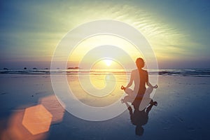 Silhouette meditation yoga woman on the background of the sea and amazing sunset