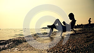 Silhouette men in chair reading book on the beach sunset