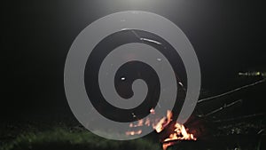 Silhouette of men sitting next to bonfire in the night.