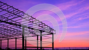 Silhouette metal warehouse outline structure in construction site against colorful twilight sky in industrial settlement are