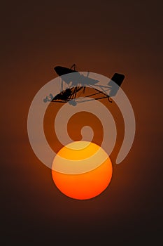 Silhouette microlight aircraft with sunset background