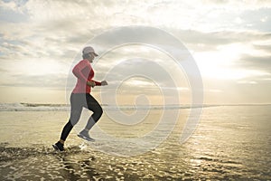 Silhouette of middle aged woman running on the beach - 40s or 50s attractive mature lady doing jogging workout enjoying fitness