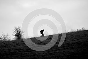 Silhouette of a military soldier, carrying a backpack, marching up a steep hill in Wiltshire, the UK