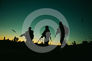 Silhouette of military soldiers with weapons at night. shot, holding gun, colorful sky. .