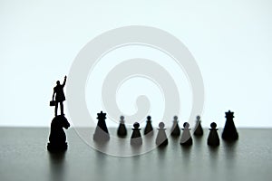 Silhouette of miniature businessman pointing upside, standing on a chess piece of horse