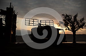 Silhouette of mobile air defence truck with radar antenna during sunset. Satellite dishes or radio antennas against evening sky