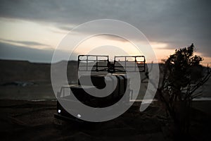 Silhouette of mobile air defence truck with radar antenna during sunset. Satellite dishes or radio antennas against evening sky