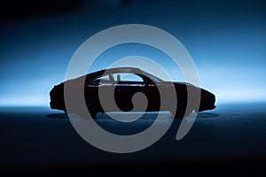 Silhouette of a model toy sports car on blue background..