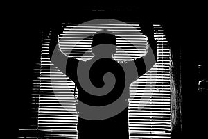 Silhouette in monochrome of a man in a window stripped pattern darkness