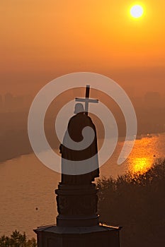 Silhouette of the Monument of Saint Vladimir Volodymyr the Great during sunrise. Morning thick fog and orange sky.