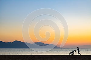 Silhouette of mother with baby stroller enjoying motherhood at s