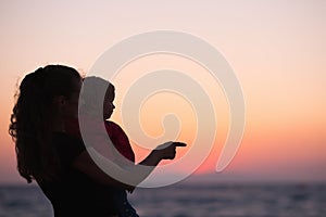 Silhouette of mother with baby in sunset on beach