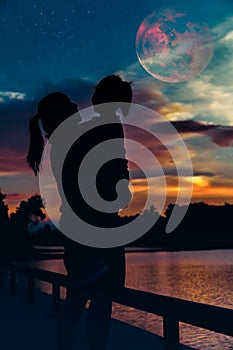 Silhouette of mother with child looking at red super moon on sky