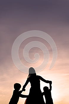 Silhouette of Mother and Children Dancing at Sunset