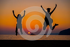 Silhouette of mother and children jumping at sunset on a beach