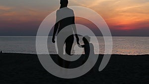 silhouette of mother and daughter going to sea at sunrise