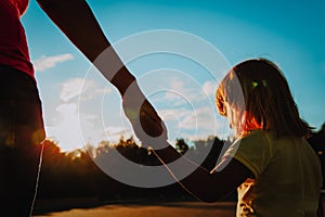 Silhouette of mother and daughter holding hands at sunset