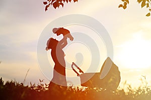 Silhouette of mother with little baby at sunset, happy family