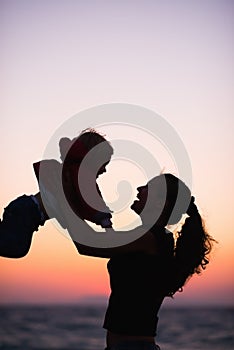 Silhouette of mother playing with baby in sunset