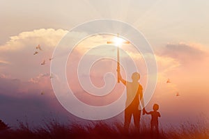 Silhouette of mother and son christian prayers raising cross while praying to the Jesus on sunset background