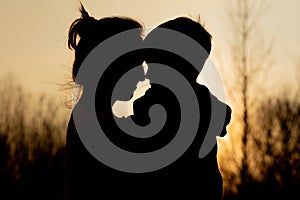 Silhouette of a mother and son playing outdoors at sunset. Mother`s day concept