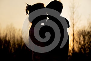 Silhouette of a mother and son playing outdoors at sunset. Mother`s day concept