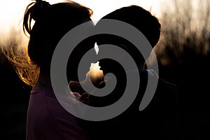 Silhouette of a mother and son playing outdoors at sunset. Mother`s day concept