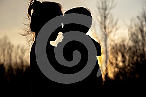 Silhouette of a mother and son playing outdoors at sunset. Mother`s day concept