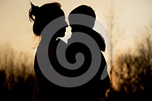 Silhouette of a mother and son playing outdoors at sunset. Mother`s day concept