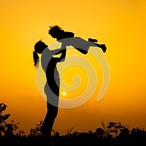 Silhouette of a mother and son who play outdoors at sunset