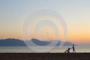 Silhouette of mother with stroller enjoying motherhood at sunset