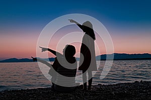 Silhouette of a mother with two daughters on a beach after sunset