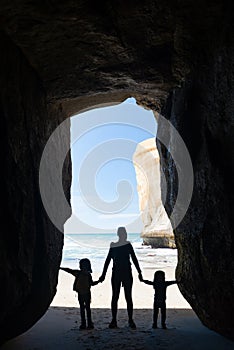 Silhouette of mother with two kids in a cave at Tunnel beach