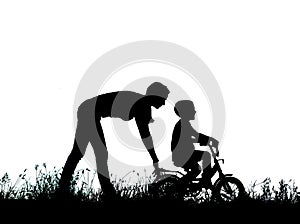 silhouette of a mother who teaches his son to ride a bike