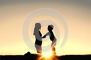 Silhouette of Mother and Young Child Holding Hands at Sunset