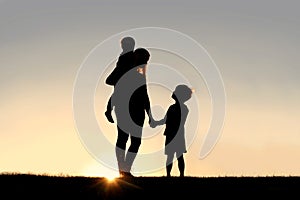 Silhouette of Mother and Young Children Holding Hands at Sunset