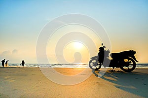 Silhouette a motorbike stands on the beach