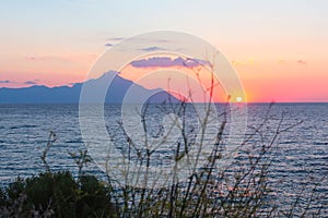 Silhouette of mount Athos at sunrise or sunset with light rays and sea panorama