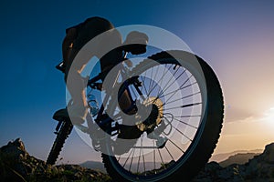 Silhouette of a mountain biker riding his mountain sportbike on top of a cliff  hill