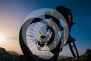Silhouette of a mountain biker riding his mountain sportbike on top of a cliff  hill