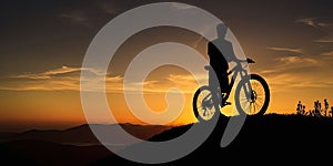 Silhouette of a mountain biker on top of a mountain during sunset