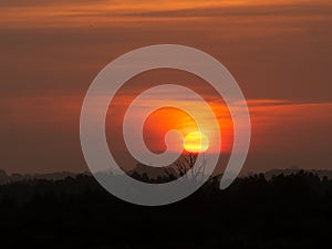 Silhouette mountain hill with big sun at sunrise sunset. Orange and yellow sky and clouds