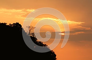 Silhouette of mountain top with golden sunset behind the clouds