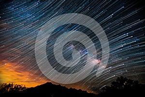 Silhouette of mountain and trees during sunset under a dark sky full of stars