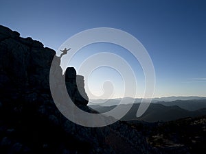 Silhouette of mountaineer descending from cliff on cliff