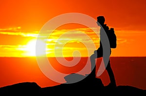 Silhouette of a mountaineer standing on the top