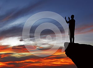 Silhouette of muslim man standing on the top of cliff