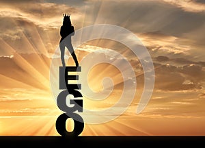 Silhouette of a narcissistic and selfish woman with a crown on her head standing on the word ego