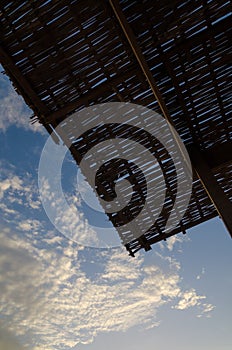 Silhouette of natural bamboo roof against beautiful blue sky with soft clouds at coast of Senegal, Africa